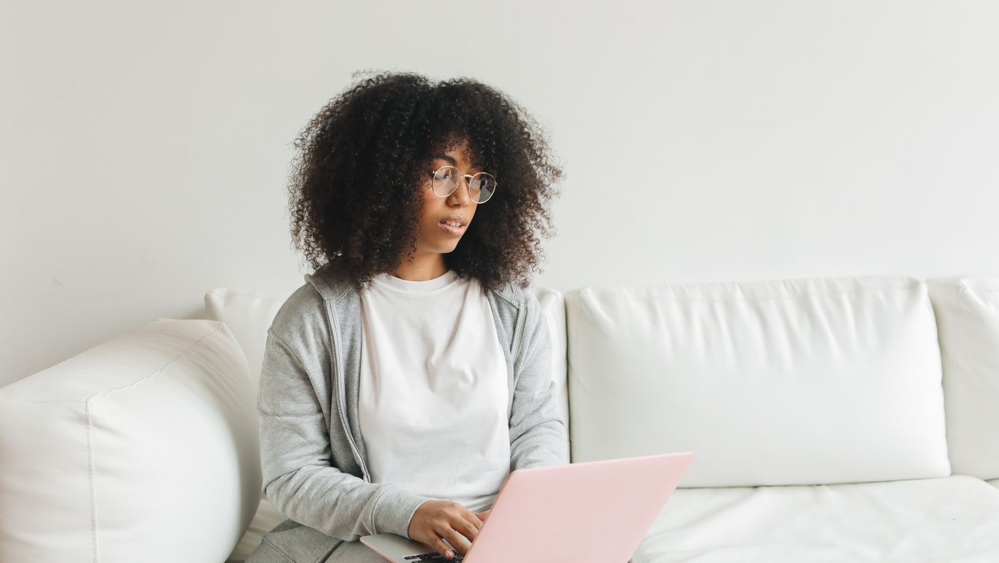 Woman studying with a laptop and notebook at home.